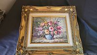 Full view of the framed original oil painting showing the bouquet of multicolored flowers in a blue vase with ornate gold frame.