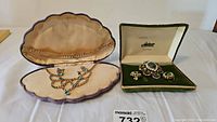 Two vintage rhinestone jewelry sets in their original display boxes, one with blue-green stones and one Astor set with green stones