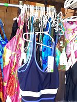 Photo showing the collection of women's bathing suits on hangers, showcasing various colorful patterns including floral and solid colors.