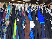 Photo showing a collection of women's bathing suits hanging on a rack, featuring various colors such as black, blue, brown, and multicolor floral prints.