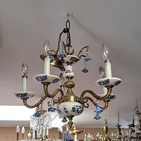 Full view of the 1940s Dutch chandelier showing the combination of brass and hand painted Delft porcelain elements with five lights and hanging blue porcelain flowers.