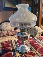 Full view of Aladdin Model No. 12 oil lamp showing metal base and decorative glass shade with pearl to clear transition.