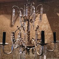 Full view of the antique Florentine bronze chandelier showing six arms and hanging crystal prisms.