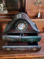 Front view of the jewelry box showing three drawers resembling book spines and a circular photo frame with a vintage photo.