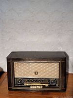Front view of Philips Jupiter 553 table top tube radio showing brown wooden cabinet and woven fabric speaker grille with brass emblem