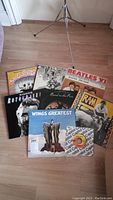 Photo showing all vinyl records in the lot laid out on the floor with varying cover designs, including Beatles, Wings, Ringo Starr and Paul McCartney albums.