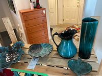 All five Blue Mountain Pottery drip ware pieces displayed on wooden bench showing varied shapes and sizes.