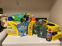 Wide view showing all cleaning supplies and trash bags together on a surface.