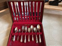 Flatware set including knives, forks, and spoons in red velvet-lined storage box