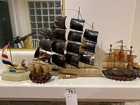 Four model ships and fisherman clown figure in a row