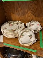 Full set of china including stacked plates, teacups on saucers, and the tea cake tier parts.