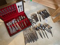 Full view of the flatware laid out on the floor next to the storage box showing all utensil types.