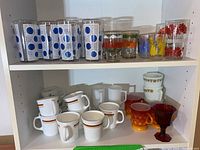 Full shelf view with assorted glassware and mugs showing various patterns and colors.