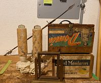 Pair of vintage floral embossed glass lamps with wooden crate boxes and spear behind arranged against wall.