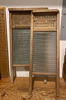 Two vintage Fraser washboards, one with glass scrubbing surface, the other with wooden slats, both showing branding from Western Broom & Woodenware Ltd., Vancouver.