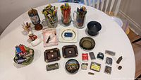 Overview photo showing all items on round table including ashtrays, lighters, swizzle sticks, matches, and coin bank