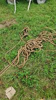 Coiled thick brown rope on grass, showing texture and condition