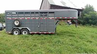 Right side exterior view showing overall trailer length, slatted sides, dual axles, spare tire mounted on side