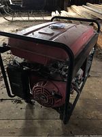 Front left angle view showing red fuel tank, recoil starter housing and tubular steel frame