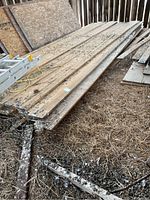 Pile of long pine boards on barn floor with ladder nearby