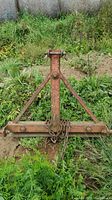 Front view of triangular steel frame with horizontal base bar and chain wrapped around center.
