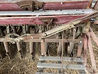 Close-up view of multiple seed drilling discs and mechanical linkage on the seed drill showing metal components and wooden frame.