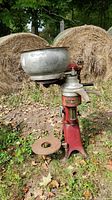 Side view photo showing the cream separator with red body, bowl on top, and crank handle on the right side.
