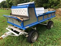 Front right view showing blue body, tufted white bench, aluminum panels, and white draw pole