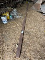 Long view of entire rusted steel beam lying on barn floor