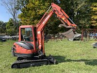 Side view of Kubota KX71-3 mini excavator with boom raised, showing tracks and enclosed cab.