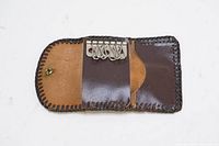 Open view of vintage leather key holder showing five metal key hooks and small leather pocket inside.