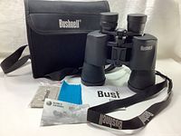 Complete set showing binoculars with strap, lens covers off, blue cleaning cloth, case, and paperwork spread out.