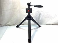 Compact black table top tripod with adjustable legs and mounting screw for camera.