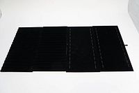 Four dark black velvet jewelry display trays stacked and shown from top view, highlighting narrow rows for holding jewelry.