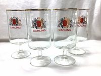 Front view of four clear beer glasses with Carling logo and gold trim on rims.