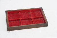 Top-down view of wooden display case showing six compartments lined with red felt.