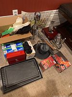 Overview photo showing all items arranged on a carpet including Ziploc bags, hand warmers, cast iron trays, milkshake maker, kitchen utensils, and gloves.