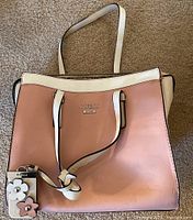 Pink and white GUESS purse showing front with attached floral keychain