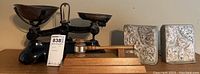 Photo showing antique Librasco metal scale with two weighing pans alongside stone bookends and wooden gavel on stand.