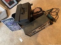 Overview of the tool lot including the black metal toolbox, part organizer, and green power grinder on carpeted floor.