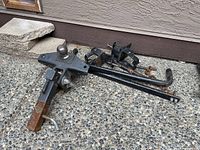 Weight distribution hitch assembly with ball mount, extending arm showing surface rust, and hardware on concrete surface near house wall.