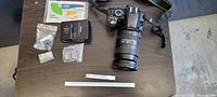 Overhead view of camera body paired with zoom lens and strap on table