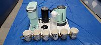 All items arranged on a white surface including mugs, kettle, frother, jug, cup warmer and Keurig machine