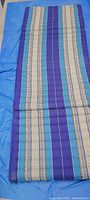 Full view of the folded meditation mat showing detailed stripe pattern in blue, purple, cream, and beige on fabric.