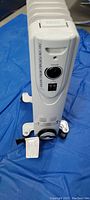Front view of white portable heater showing control panel with thermostat knob and power switches.
