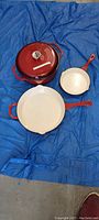 Top view of the two frying pans and stock pot with lid placed on a blue surface
