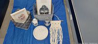 Photo showing all items including the storage basket, Buddha head, framed print, decorative tray, bottle, candle holder and macrame wall hanging