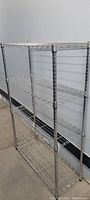 Full view of the metal wire utility shelving unit showing four shelves and vertical poles.