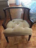 Front view showing the cane weave back and sides with the cushioned seat on wood frame.