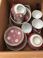 Photo of assorted pieces of the tea set including teacups, side plates, and a portion of the pitcher.